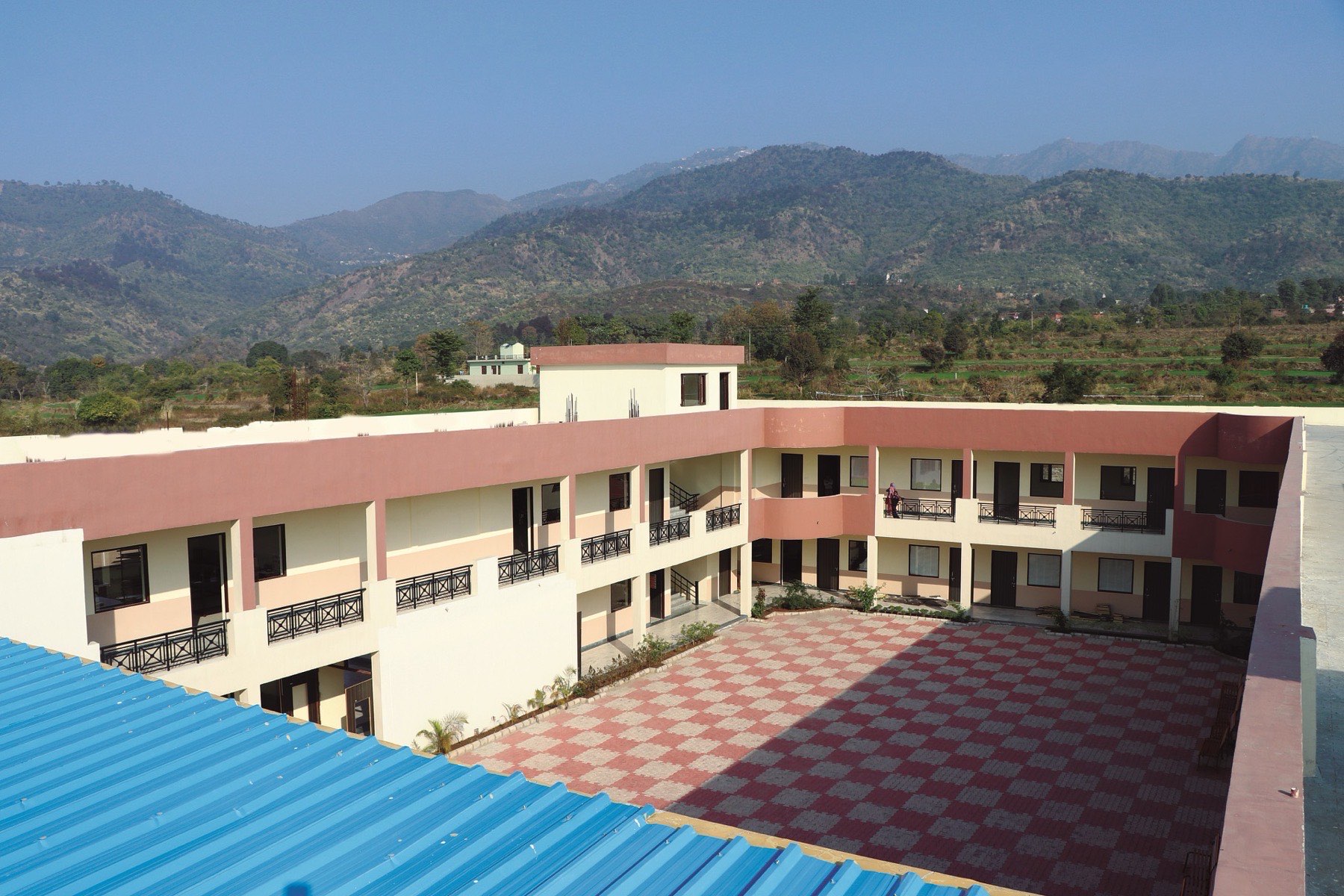 School buildings with the forested Shivalik hills rising directly behind
